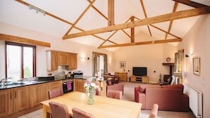A spacious living area with a wooden dining table, a sofa, and a TV.