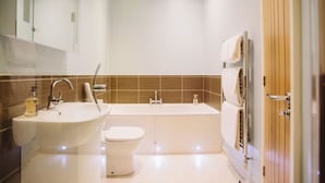 A modern bathroom with a sink, toilet, and bathtub.