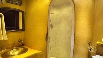 A bathroom with a large mirror, a sink, a toilet, and a shower area.