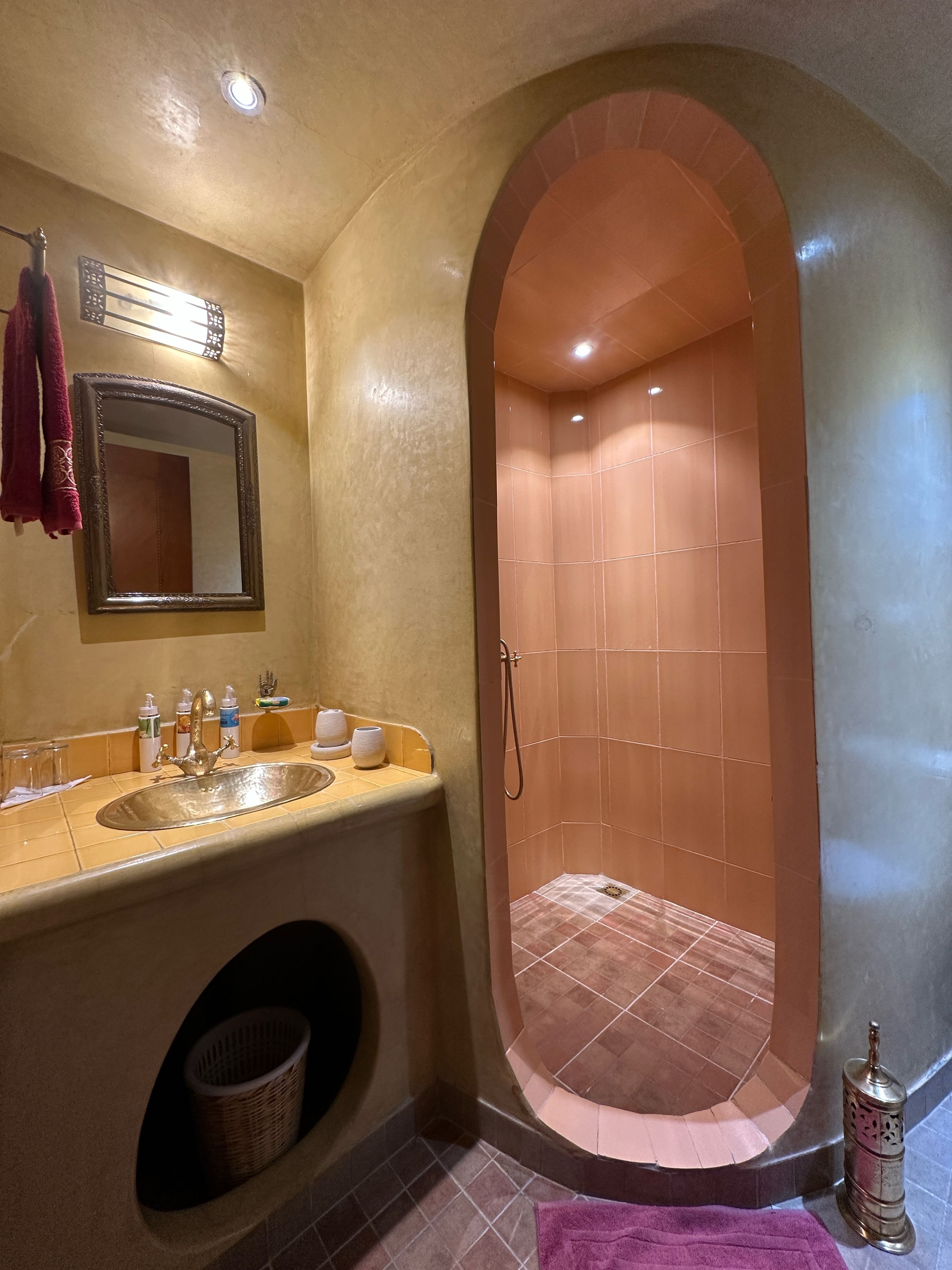 A bathroom with a vanity, a mirror, a shower enclosure, and a towel rack.