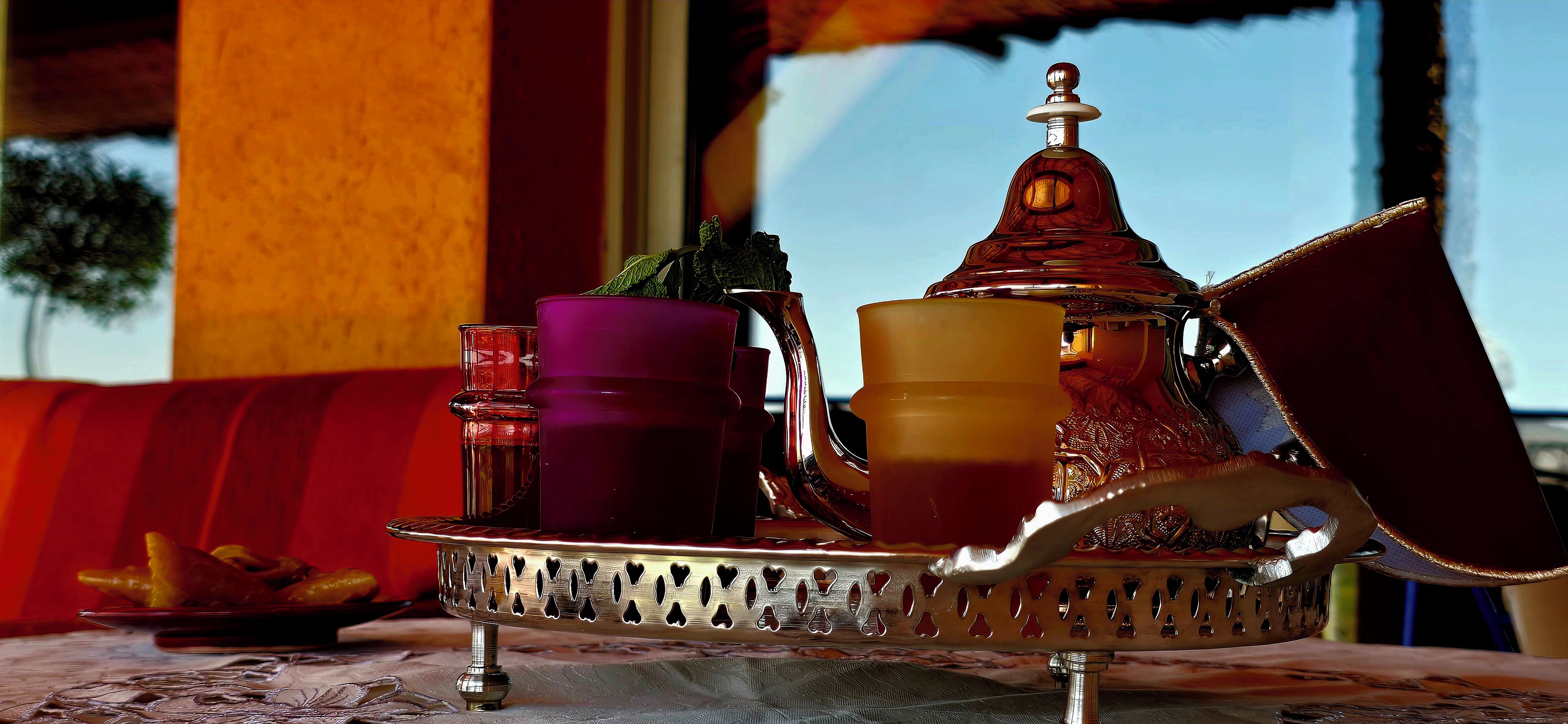 Un juego de té marroquí tradicional con tetera, tazas y bandeja sobre una mesa.