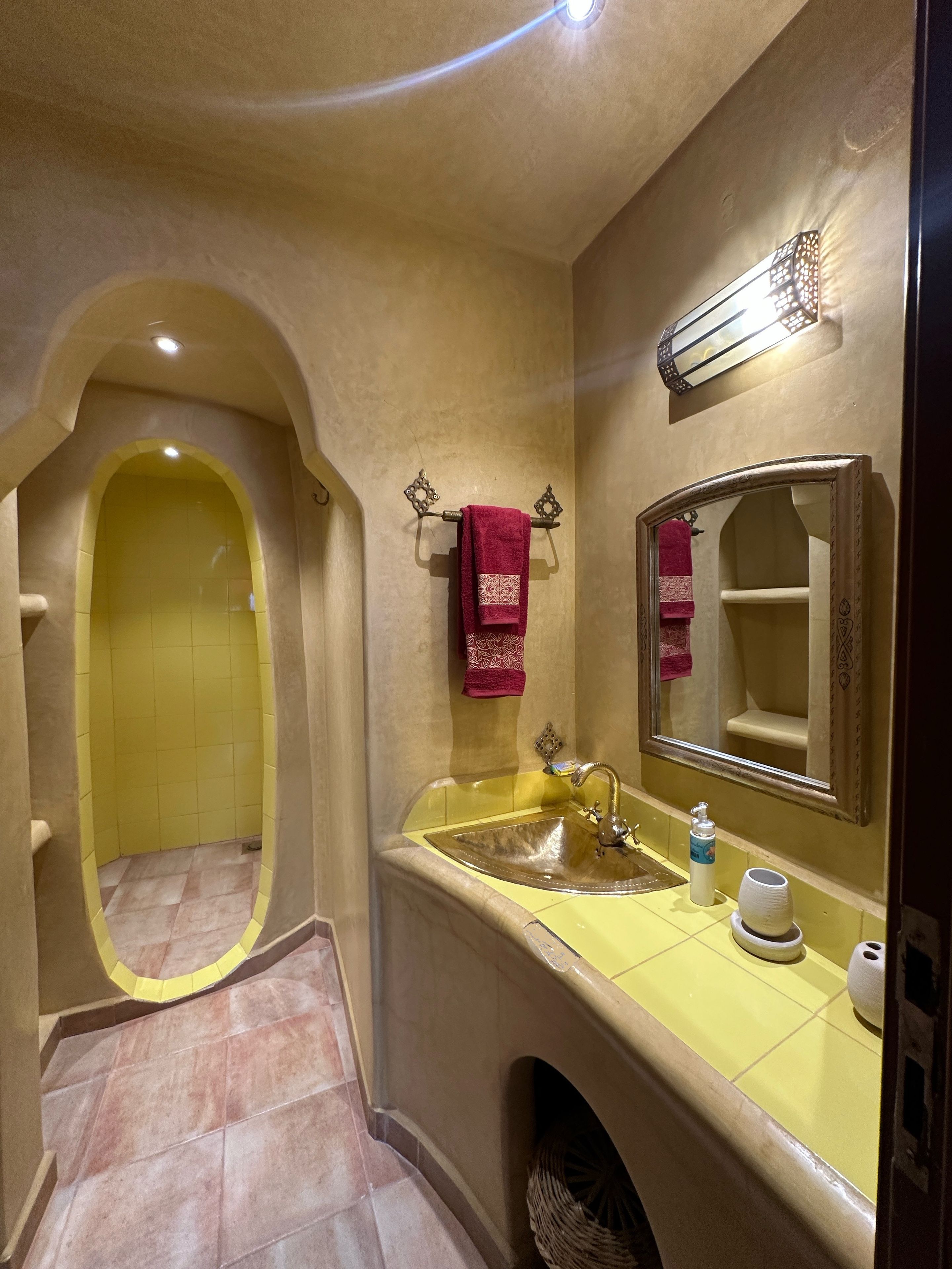 A bathroom with a yellow sink, a mirror, a towel rack, and a bathtub.