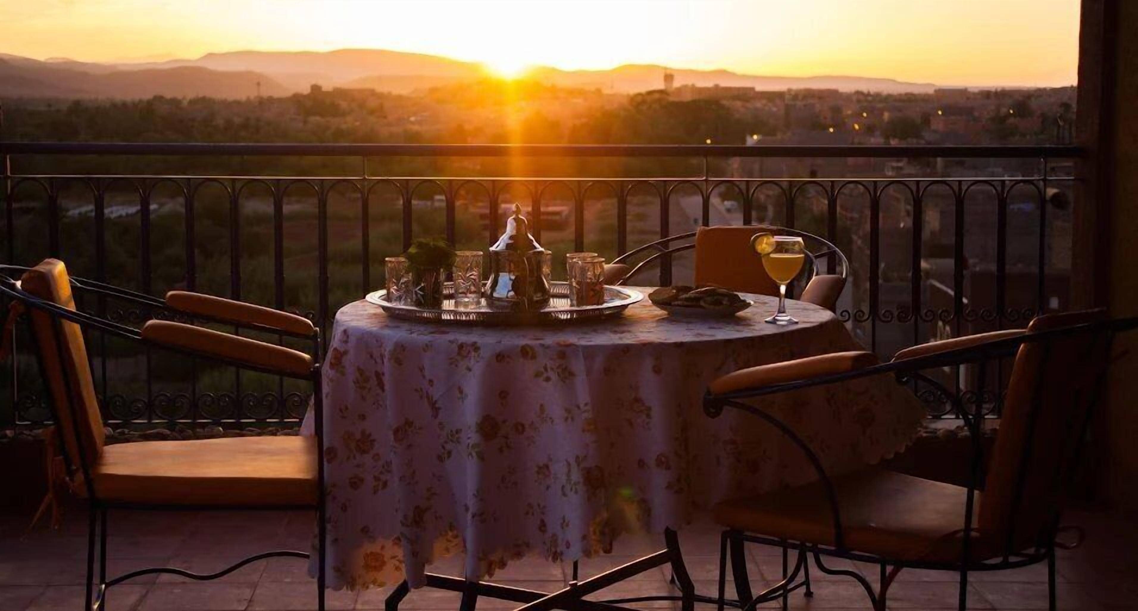 A table set for two with a view of the sunset over a cityscape.