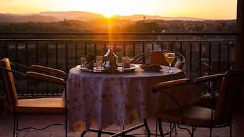 A table set for two with a view of the sunset over a cityscape.