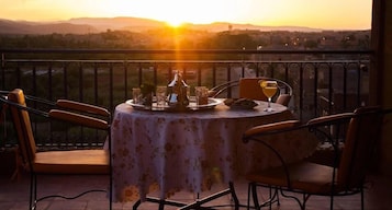 Una mesa para dos con vista al atardecer sobre un paisaje urbano.