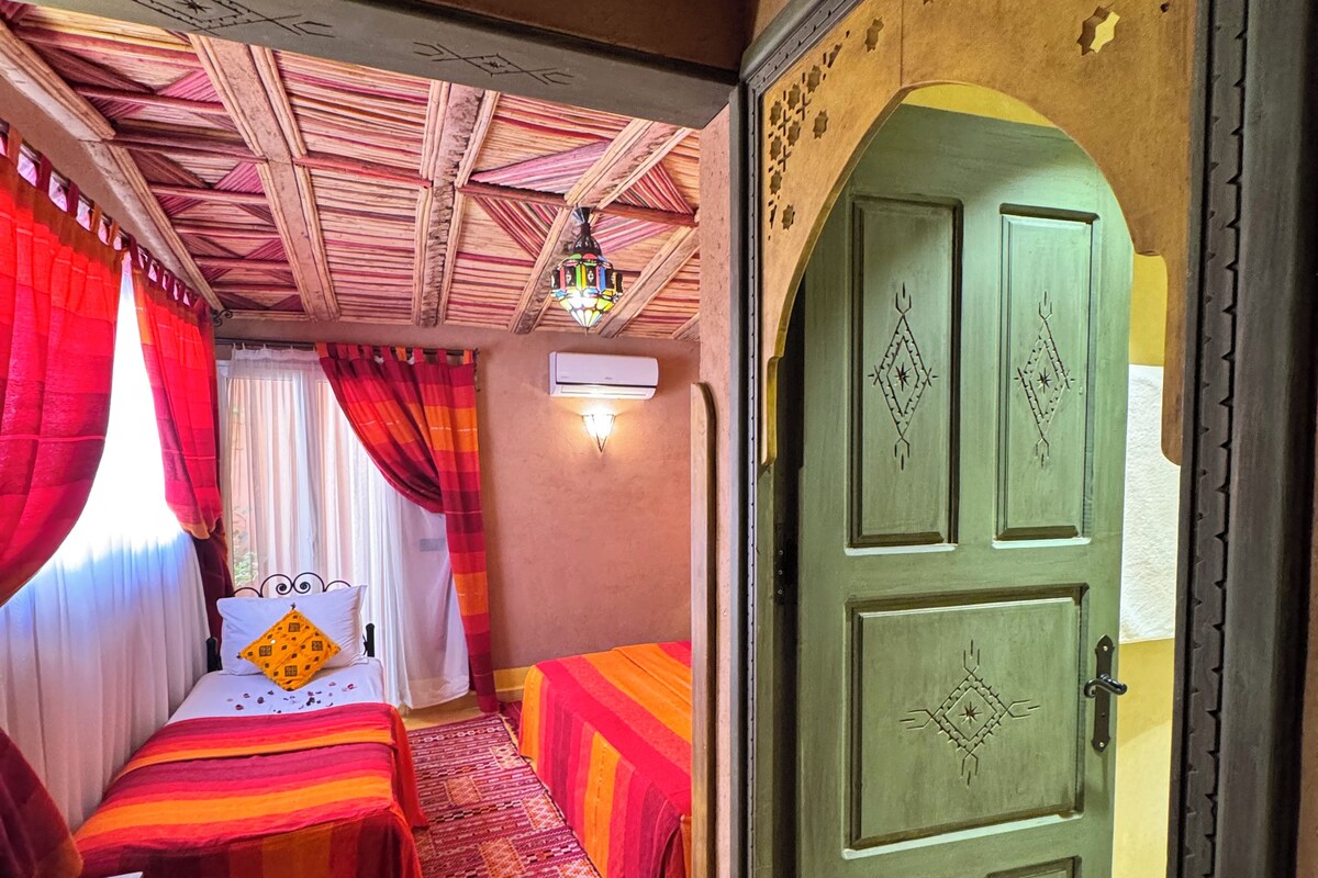 A room with a bed, a desk, and a door.