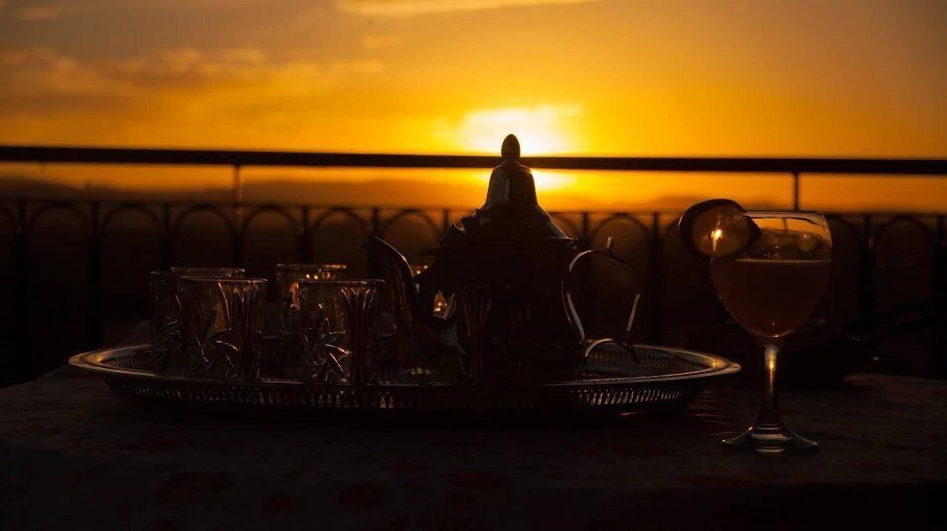 Una mesa dispuesta con vasos y una tetera al atardecer.