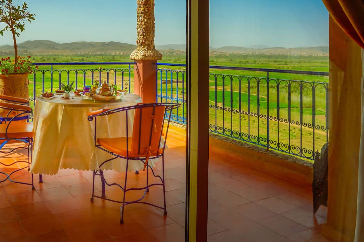 A balcony with a table set for a meal, a chair, and a potted plant.