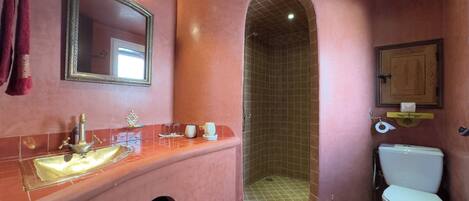 Un baño con tocador, lavamanos, espejo y cabina de ducha.