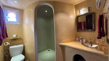 A bathroom with a toilet, sink, and shower area.