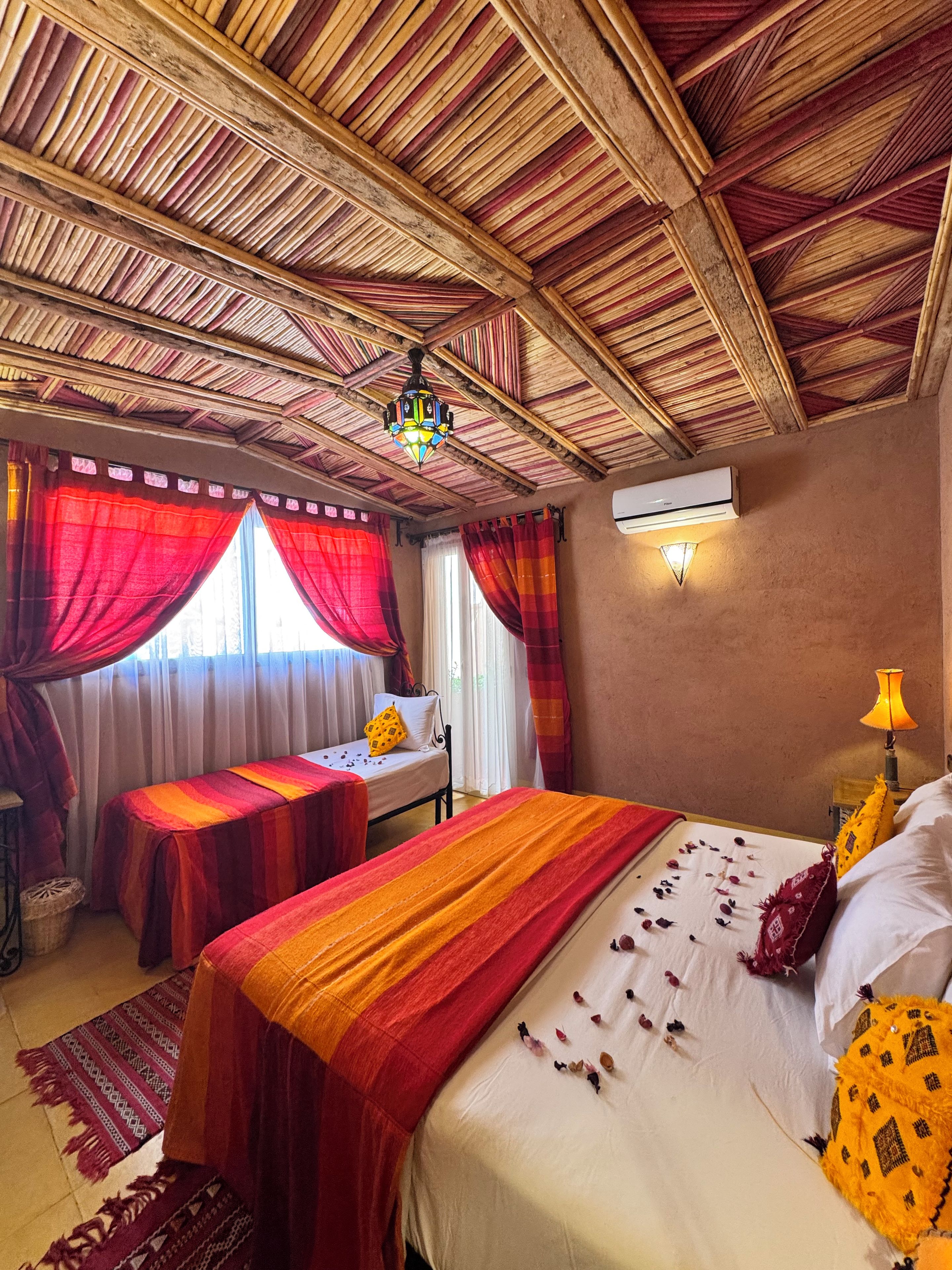 A room with a bed, two bedside tables, a ceiling fan, and an air conditioning unit.