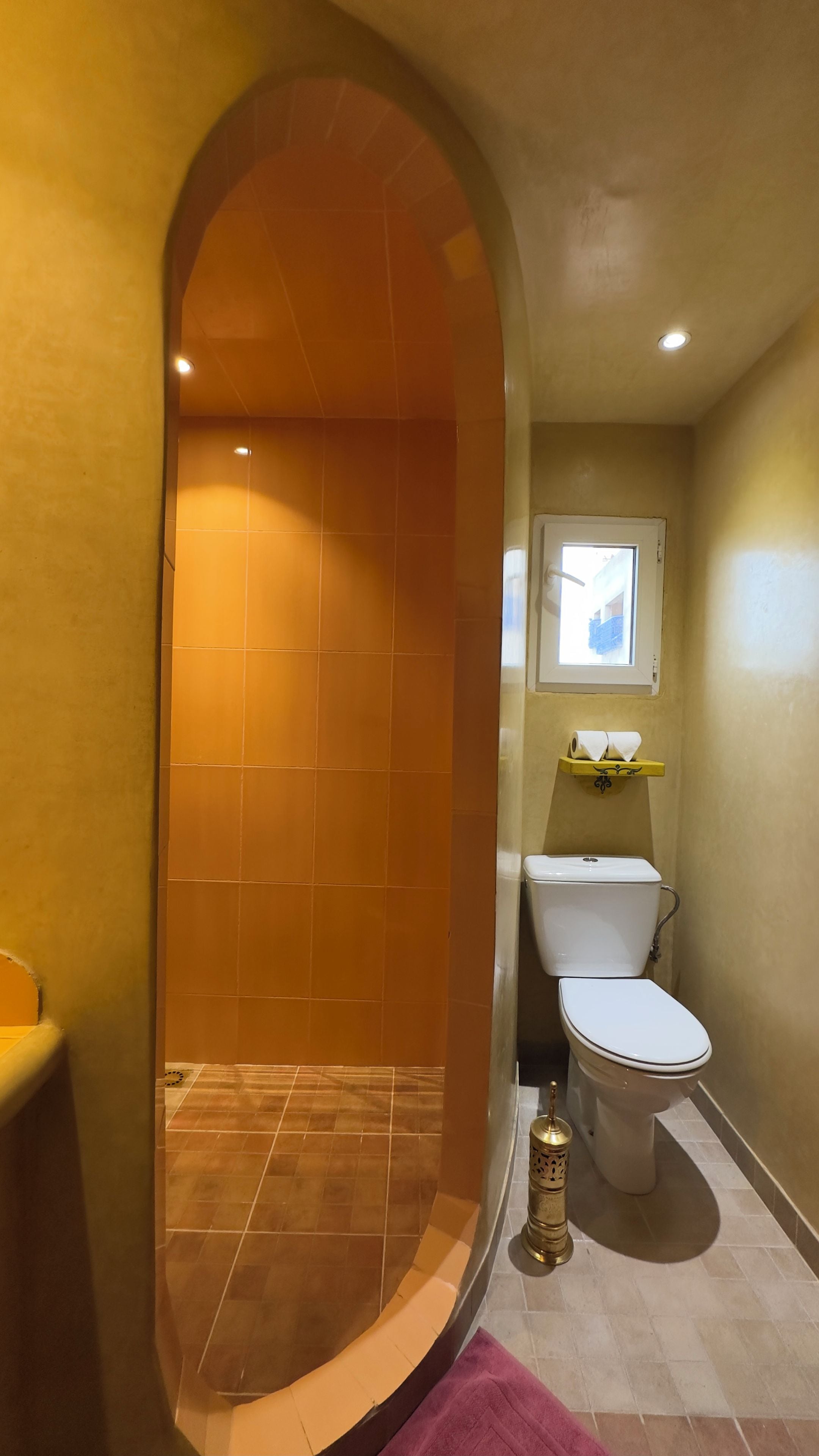 A bathroom with a shower, toilet, and a window.