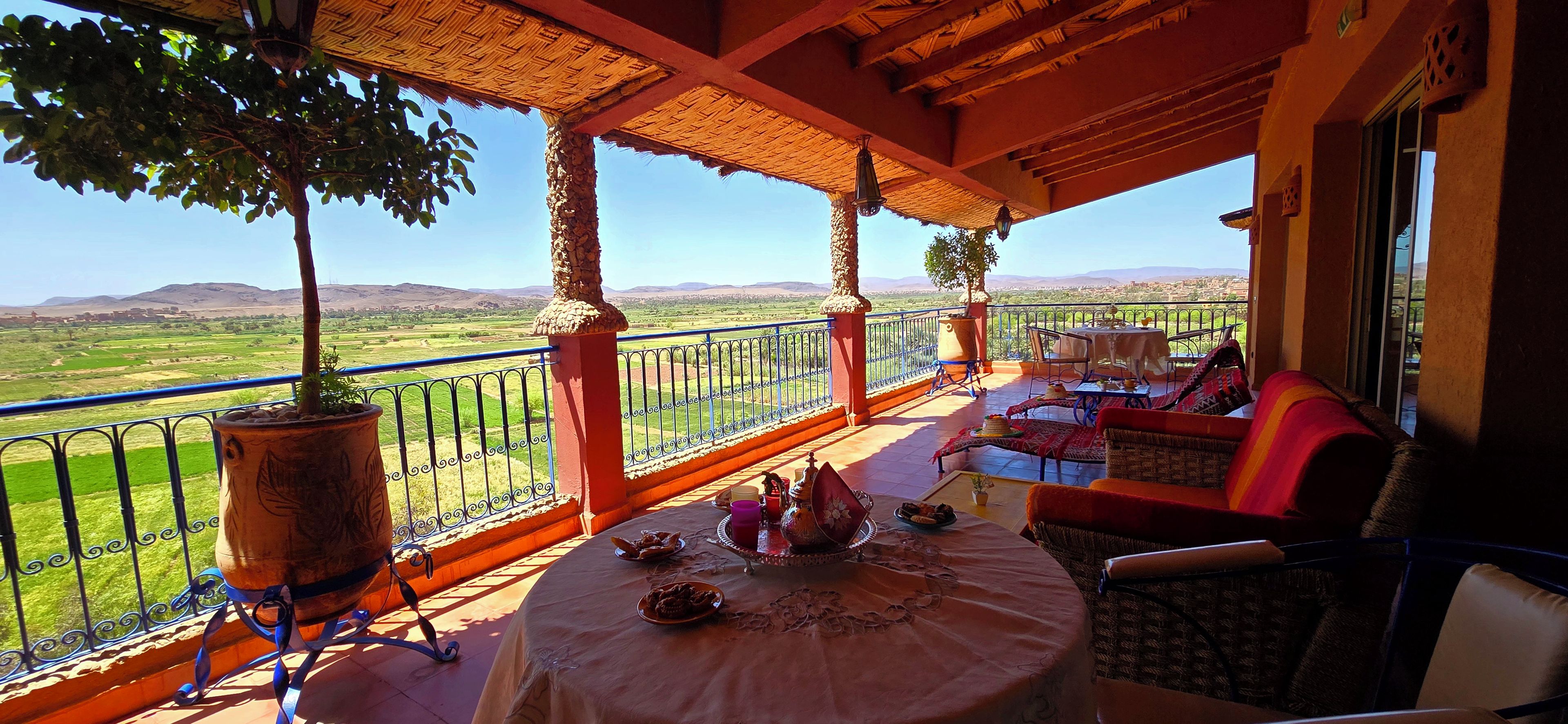 A terrace with a table set for dining, a sofa, and a view of the countryside.
