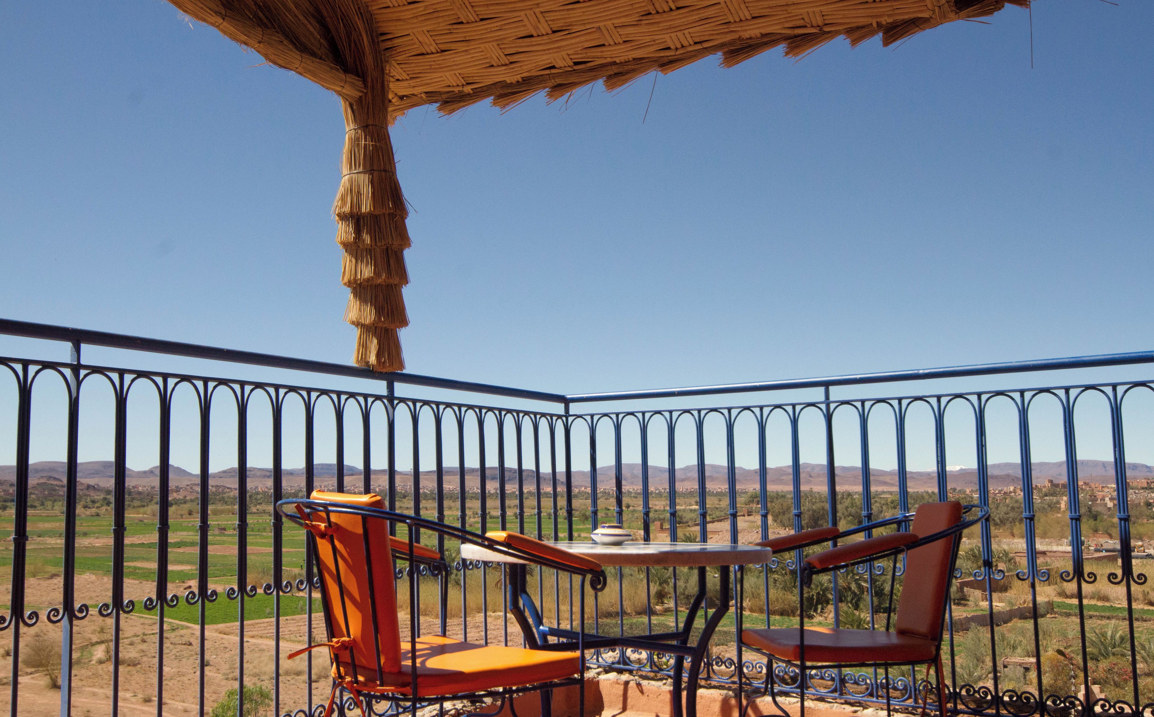 Un balcone con un tavolo e due sedie, affacciato su un paesaggio collinare e ricco di vegetazione.