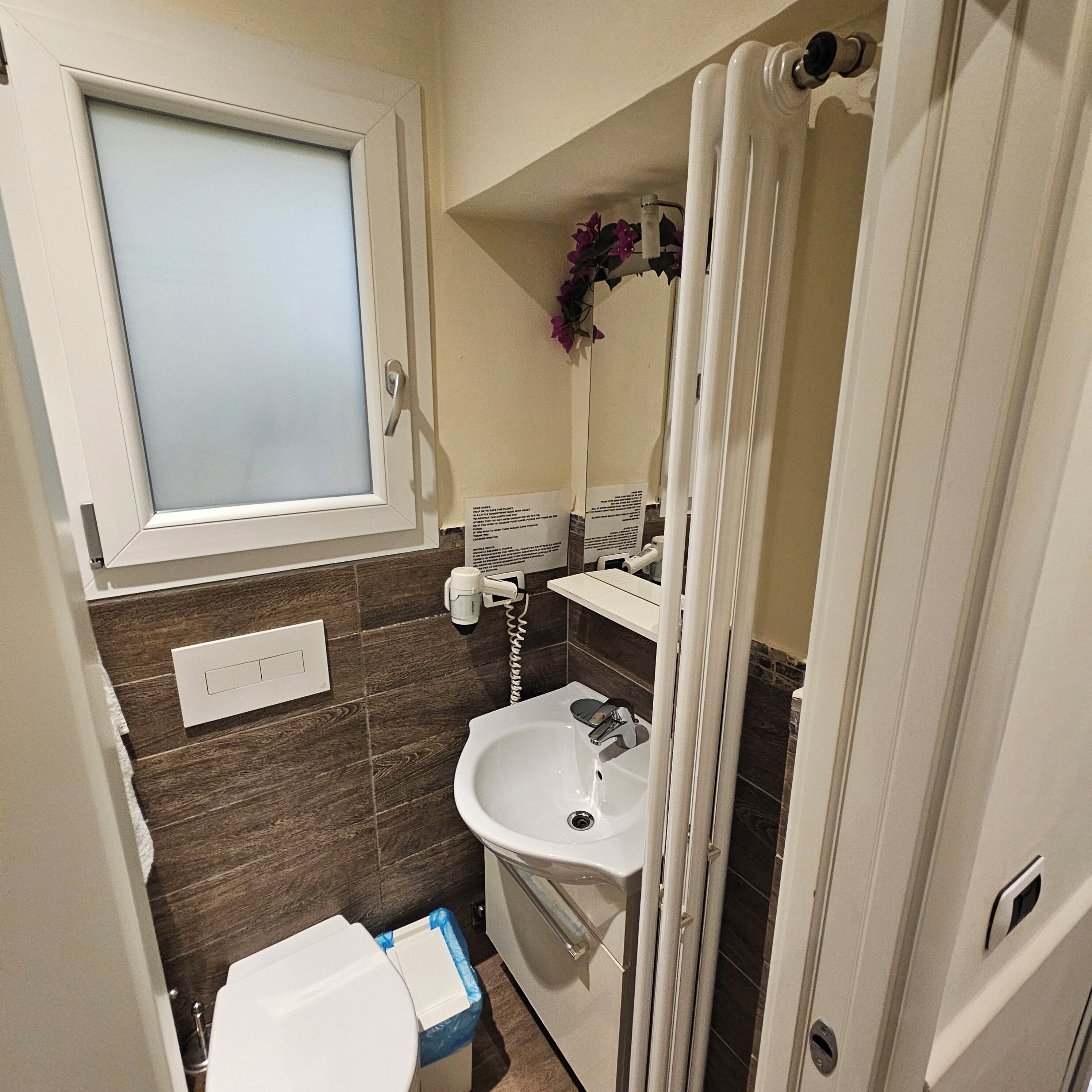 Een kleine badkamer met toilet, wastafel en raam.