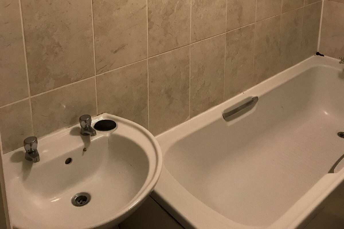 A bathroom with beige tiles, a sink, and a bathtub.