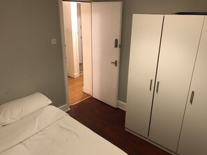 A bedroom with a bed, a wardrobe, and a door leading to another room. - Rooms at 5 Hammersmith Road - Hostel (London)