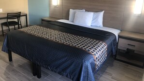 A hotel room with a bed, bedside tables, a desk, and a chair. - Luxury Inn & Suites (Houston)