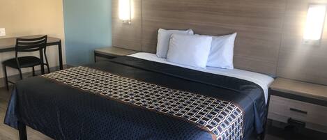 A hotel room with a bed, bedside tables, a desk, and a chair.
