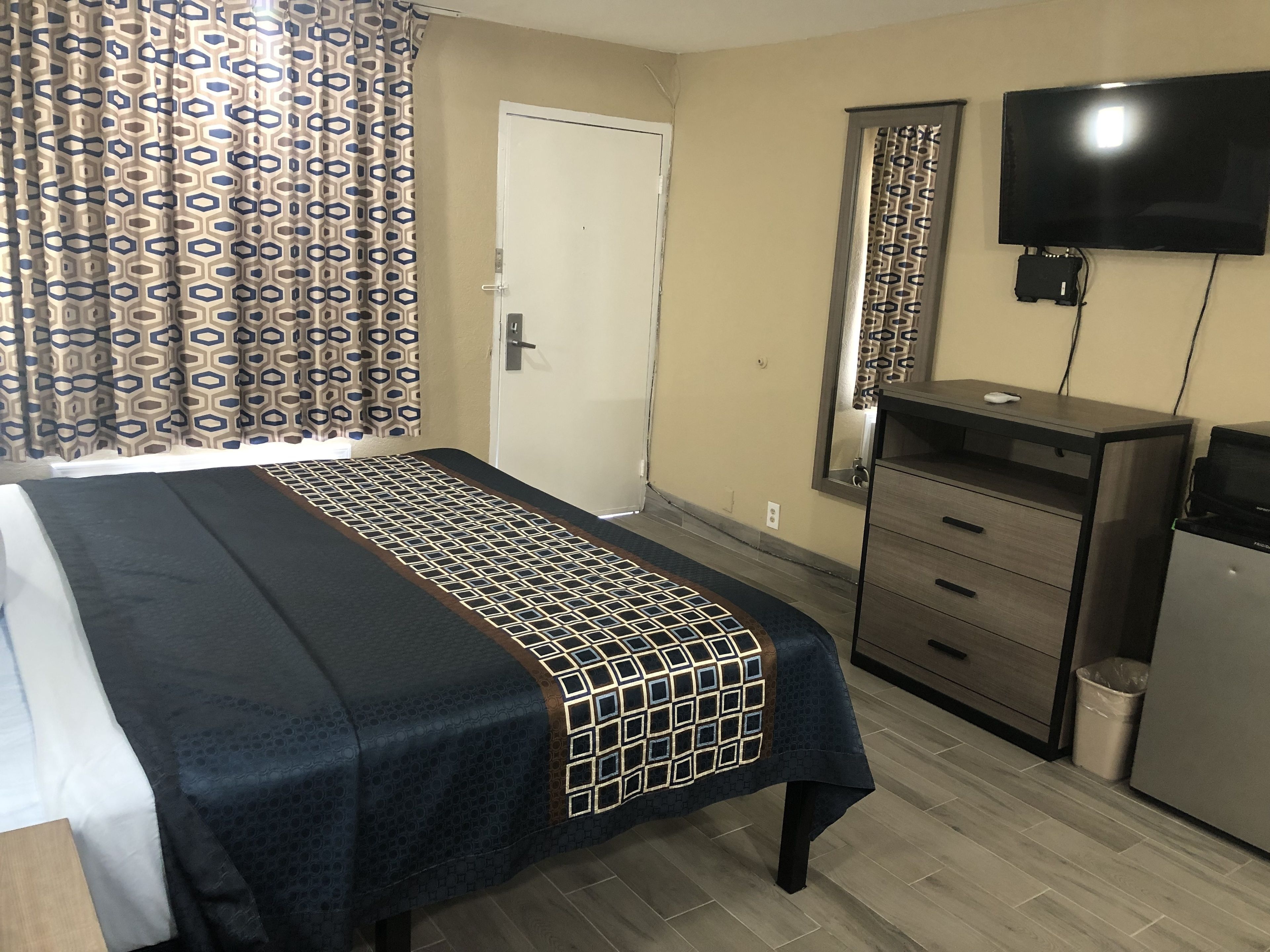 Una habitación de hotel con una cama, un escritorio, un televisor y un espejo.