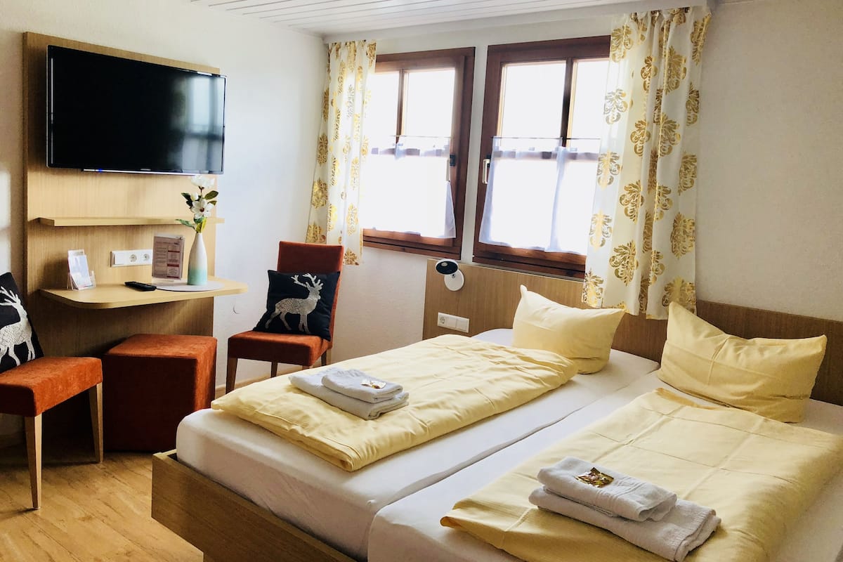 Une chambre d’hôtel avec un lit, un bureau, une chaise, une télévision et des rideaux.