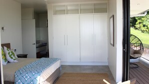 A bedroom with a bed, a wardrobe, and a view of the outdoors. - Nikao Luxury Villa (Rarotonga)