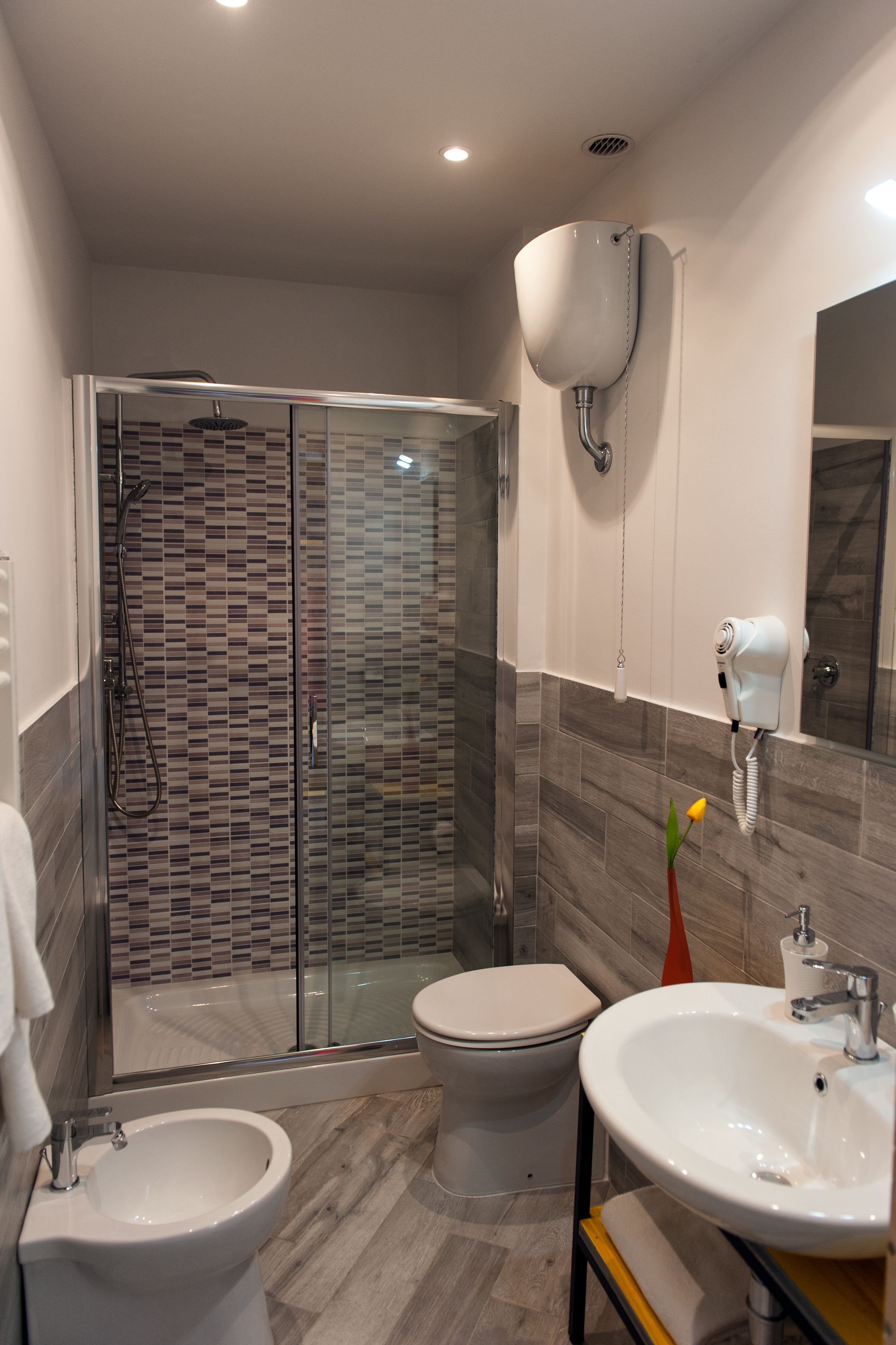 Une salle de bain moderne dotée d’une douche à parois de verre, de toilettes, d’un bidet et d’un lavabo avec un miroir.