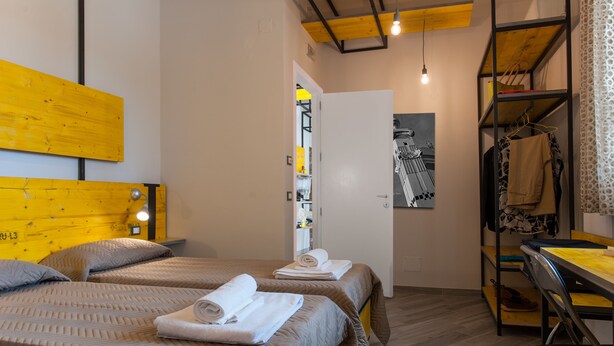 A hotel room with two beds, a desk, and a wardrobe. - L'Officina di Apollo (Palermo)