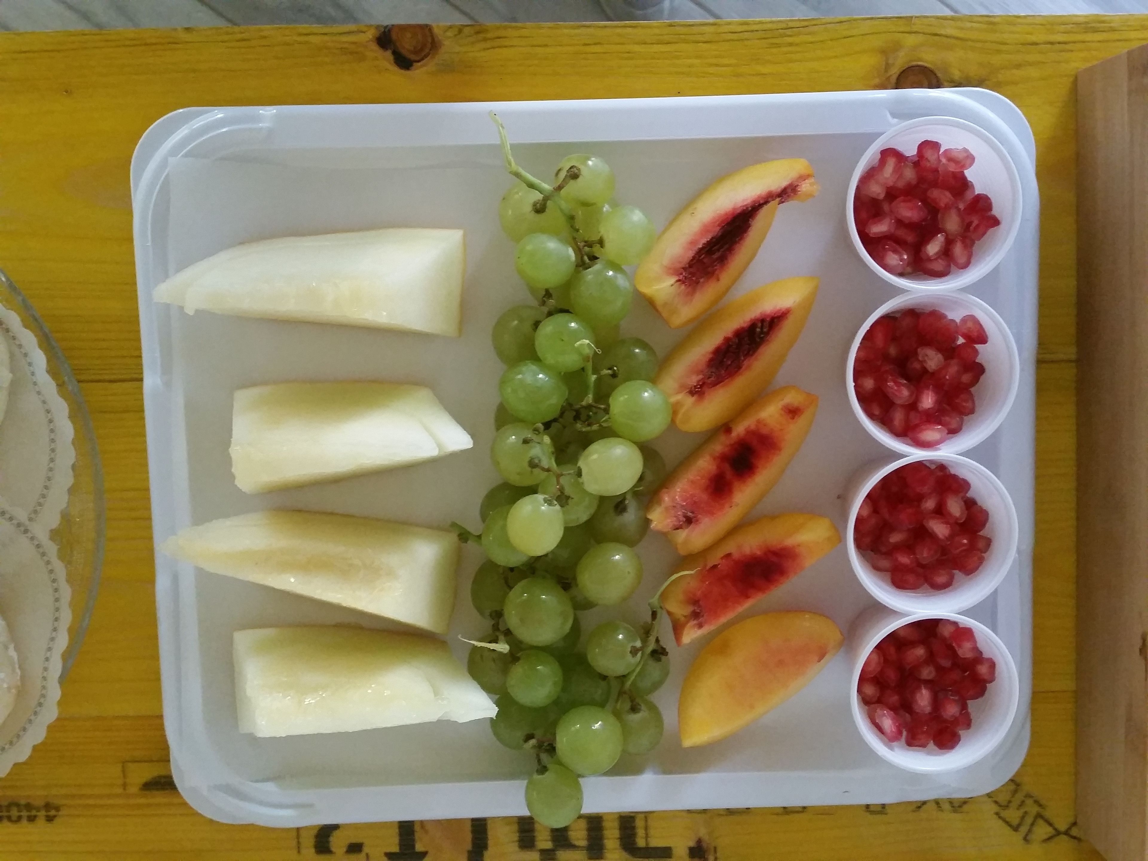Uma bandeja com frutas fatiadas e uvas.