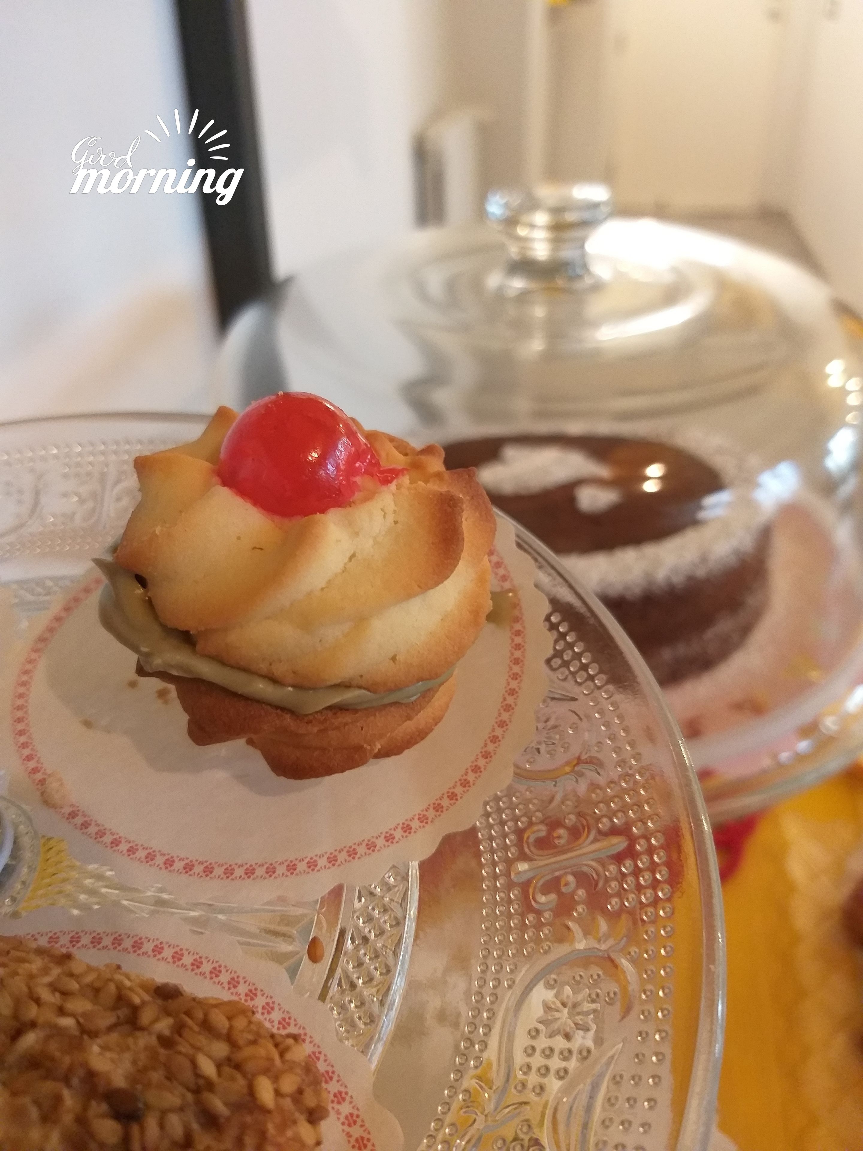 Un postre en un plato de cristal con una cereza encima.