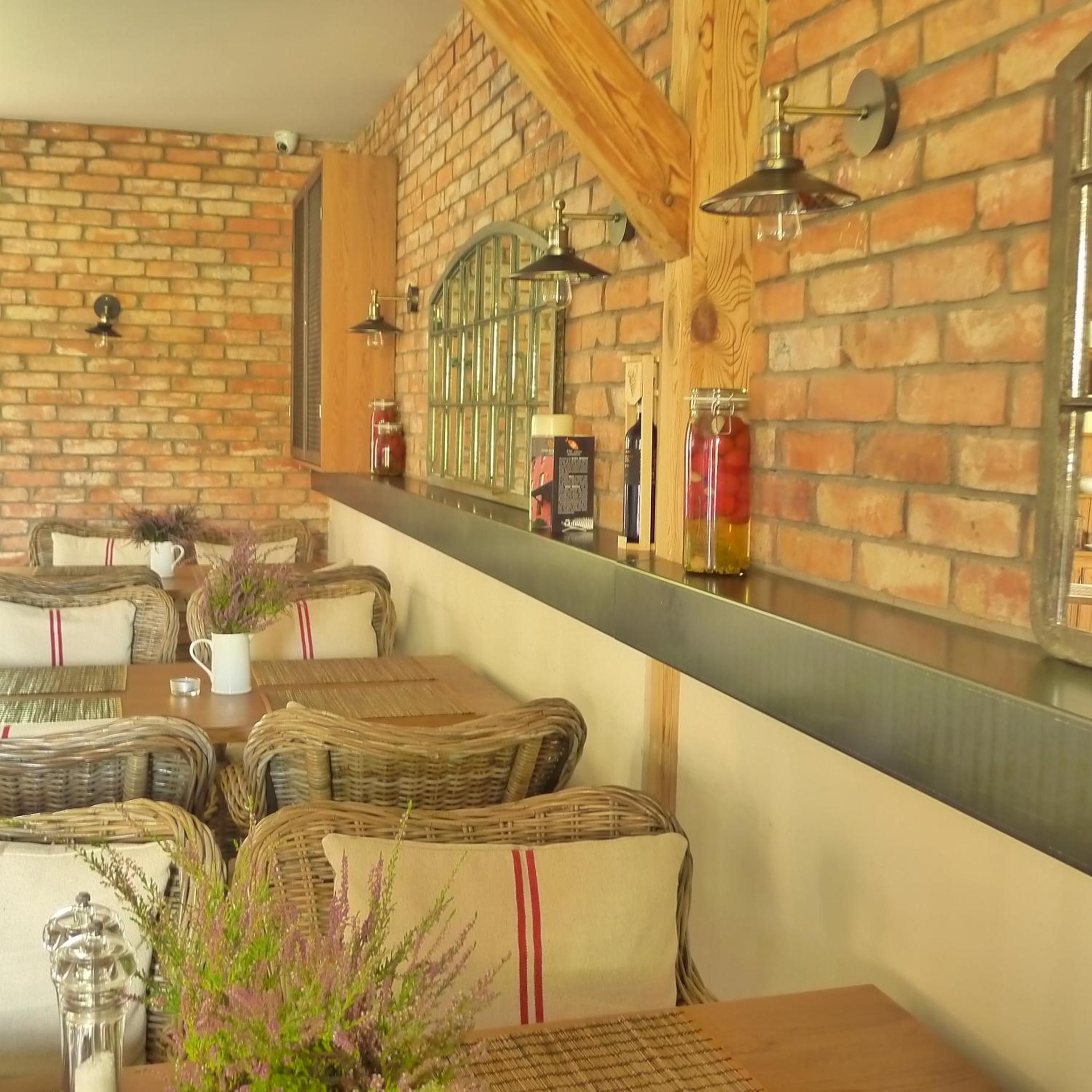 A restaurant with brick walls, wooden beams, and wicker furniture.