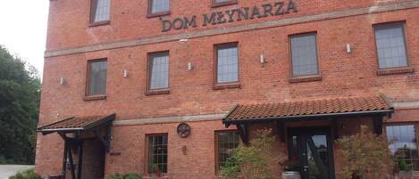 A two-story brick building with the name 'DOM MEYNARZA' on the facade.