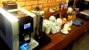 Un espace dédié au café, équipé d’une machine à café, d’un distributeur d’eau et d’une variété de tasses et de soucoupes.