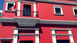 Un edificio rojo con detalles blancos y numerosas ventanas.