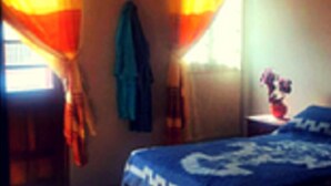 Una habitación con cama, una ventana con cortinas y un objeto fijado a la pared.
