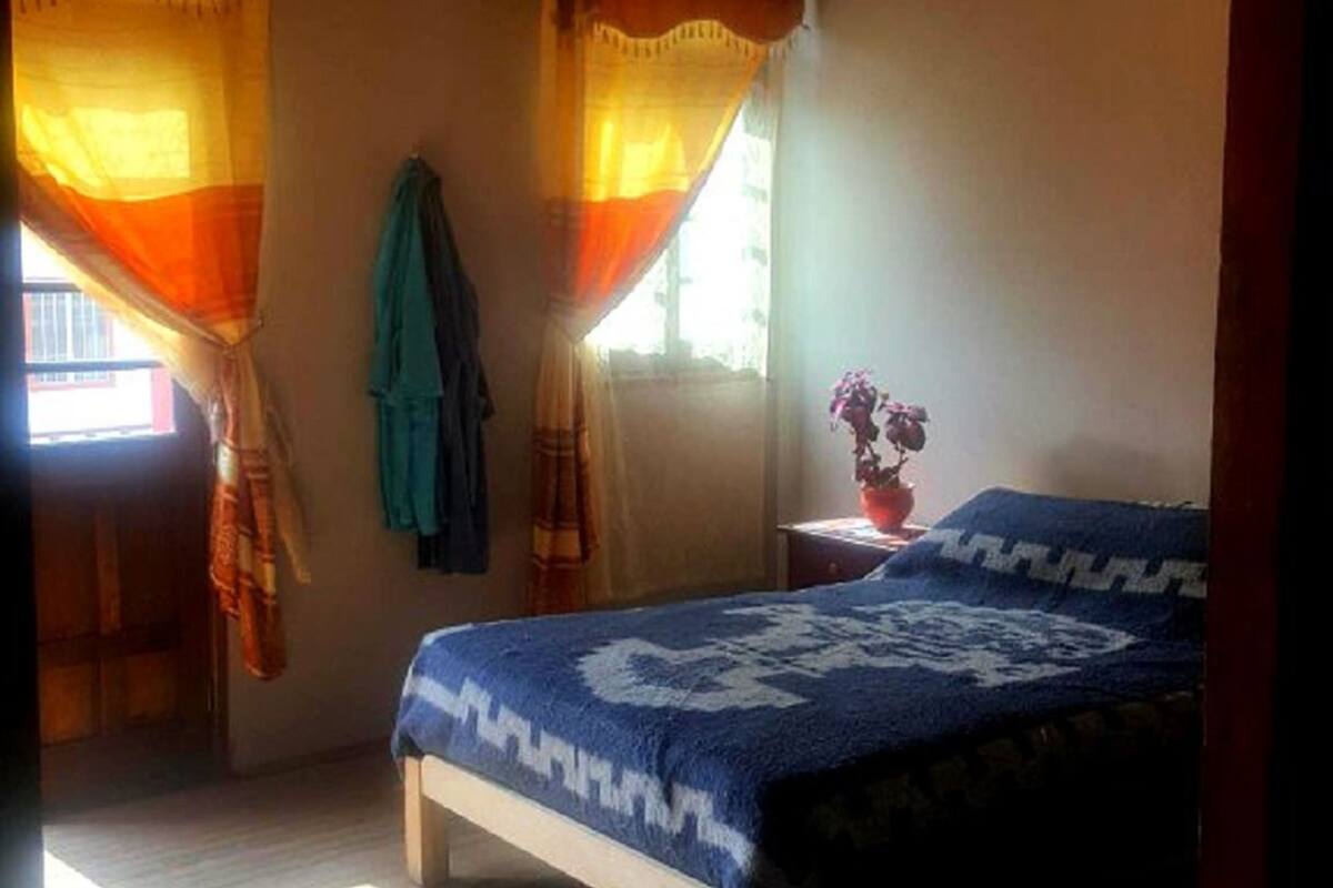 Una camera da letto con un letto, una finestra con tende, una sedia e un tavolo.
