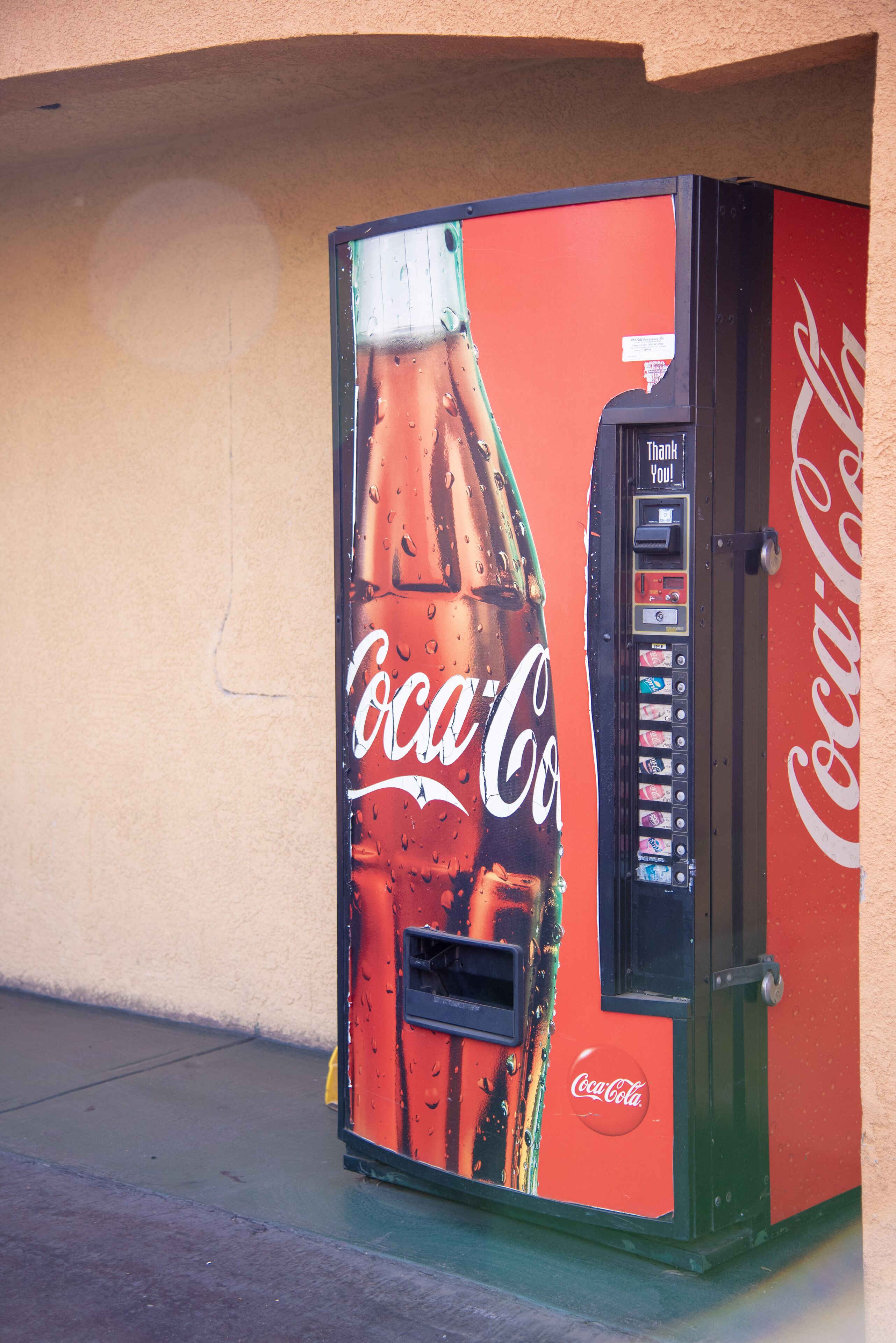 A Coca-Cola vending machine with a large advertisement of a Coca-Cola bottle.