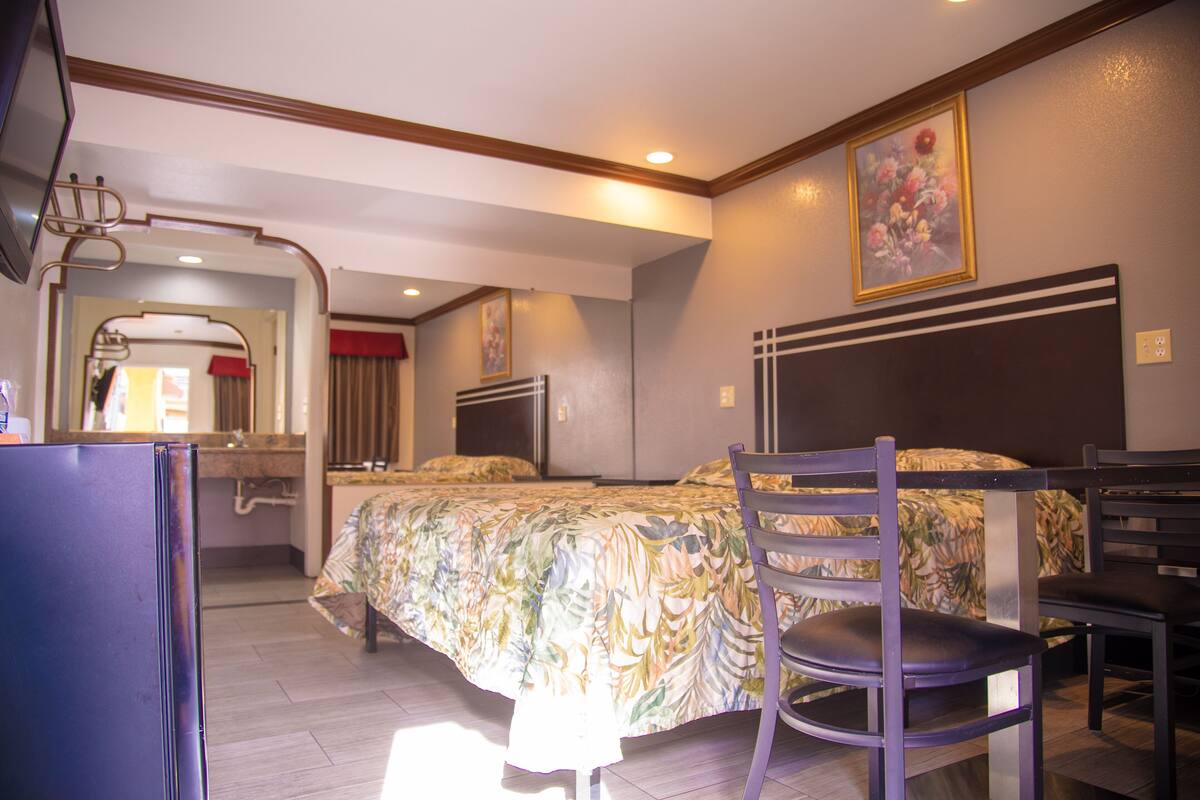 A hotel room with a bed, a chair, a desk, a mirror, and a television.