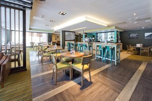 A modern hotel lobby with a bar area, seating arrangements, and a view through large windows. - Premier Inn Newbury TC - London Road (Newbury)