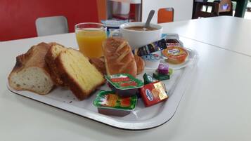 A tray with breakfast items including bread, juice, coffee, and various spreads.