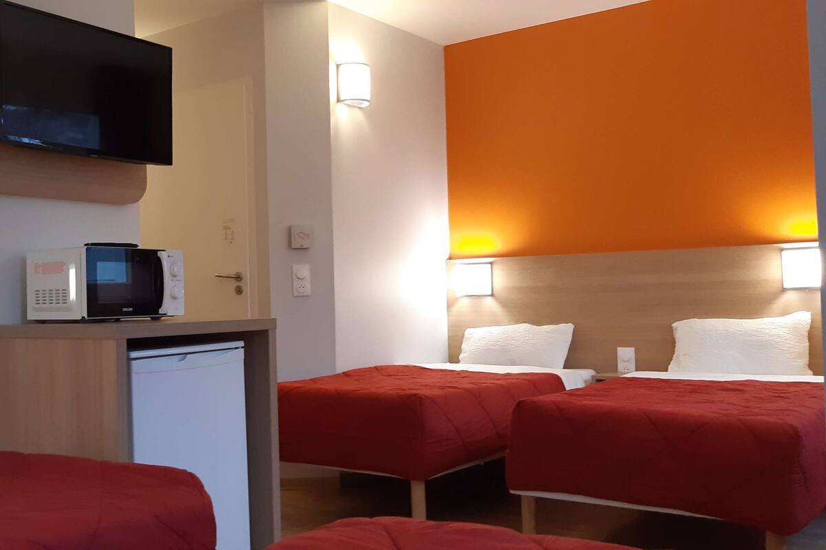 Ein Hotelzimmer mit zwei Betten, einem Fernseher, einer Mikrowelle und einem kleinen Kühlschrank.