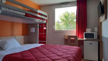 Una habitación con literas, un escritorio con silla, un microondas y un televisor.