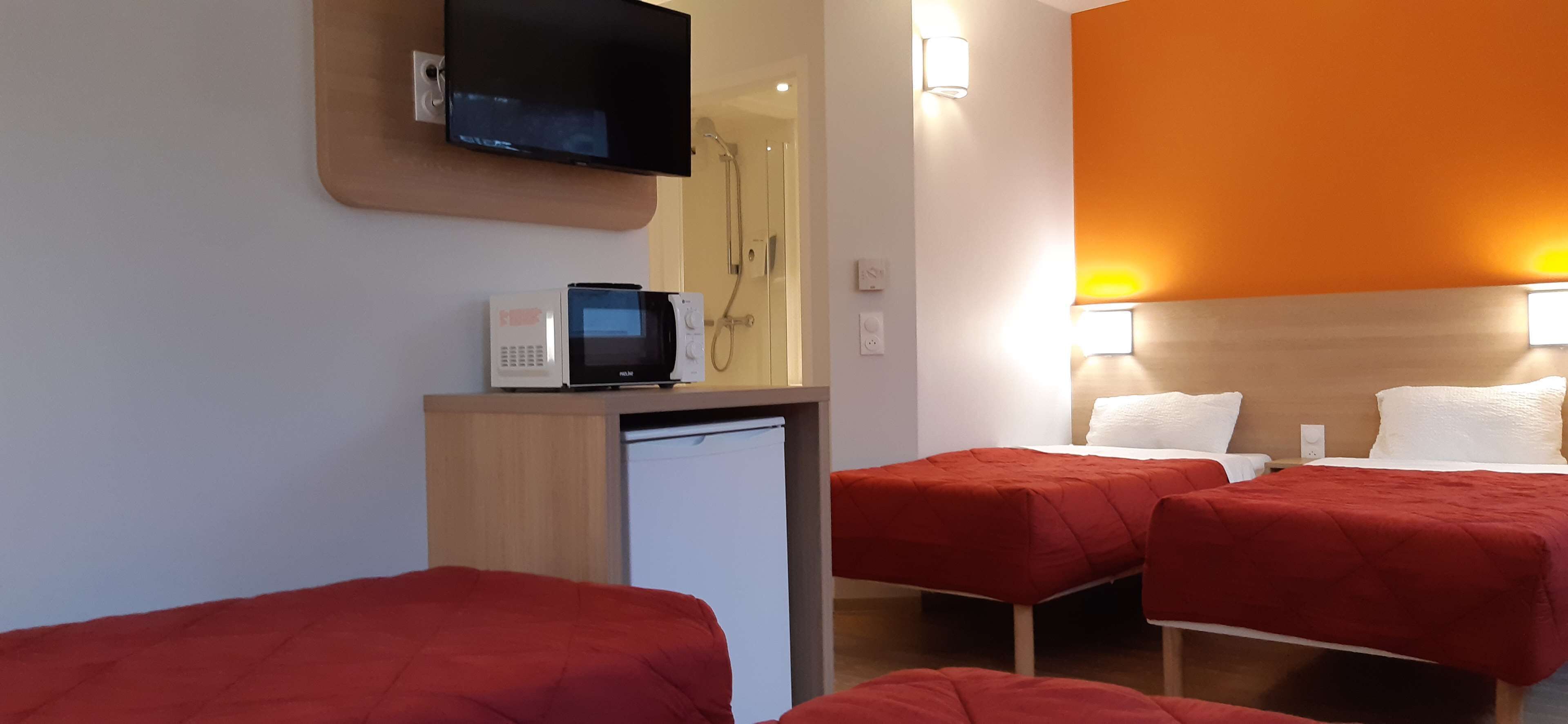 Habitación de hotel con dos camas, televisión, microondas y refrigerador pequeño.