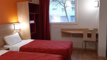 Une chambre d’hôtel avec deux lits, un bureau et une chaise.