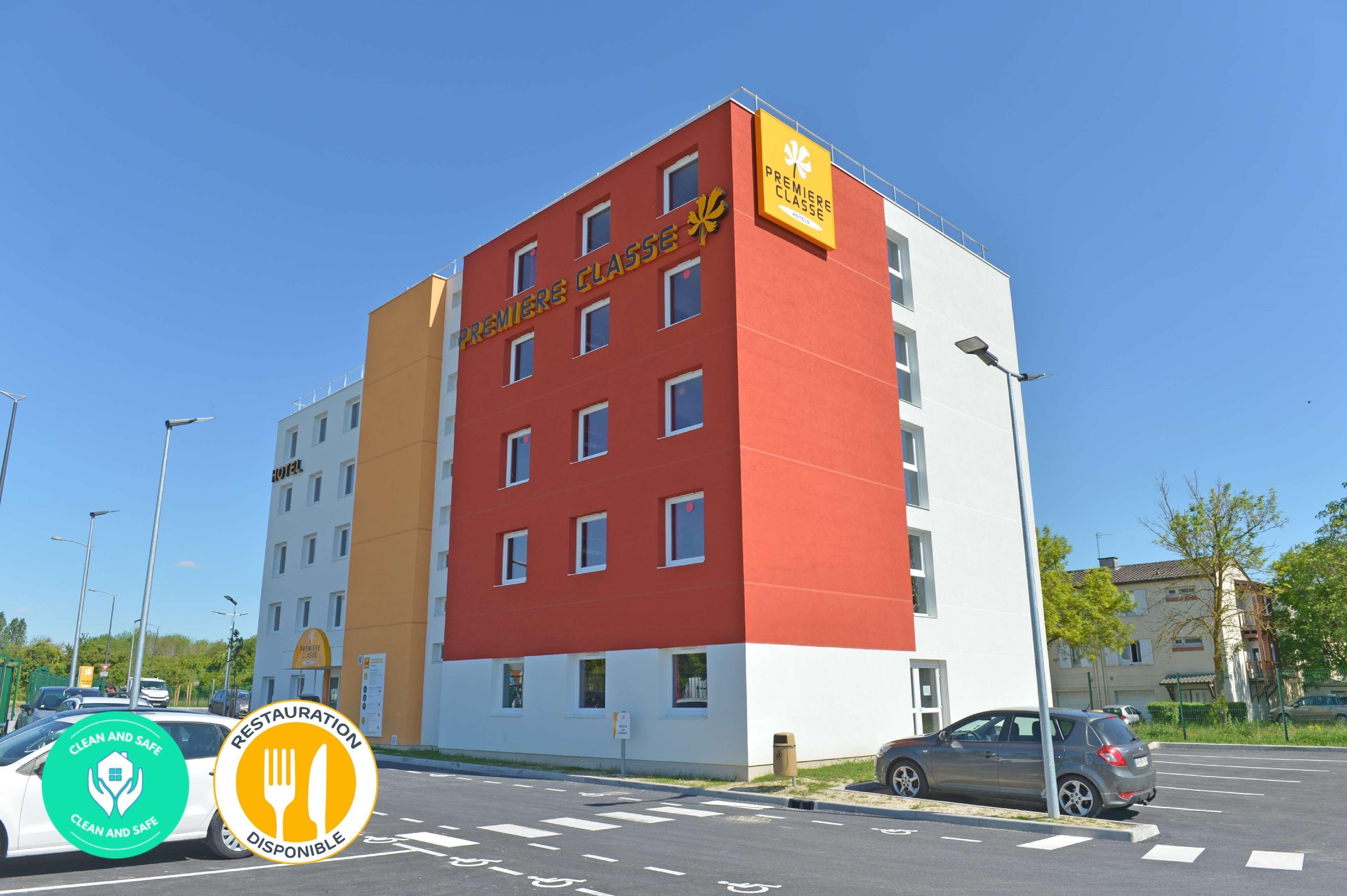 Un edificio de varios pisos con fachada roja y blanca, que muestra un letrero que dice Premiere Classe.