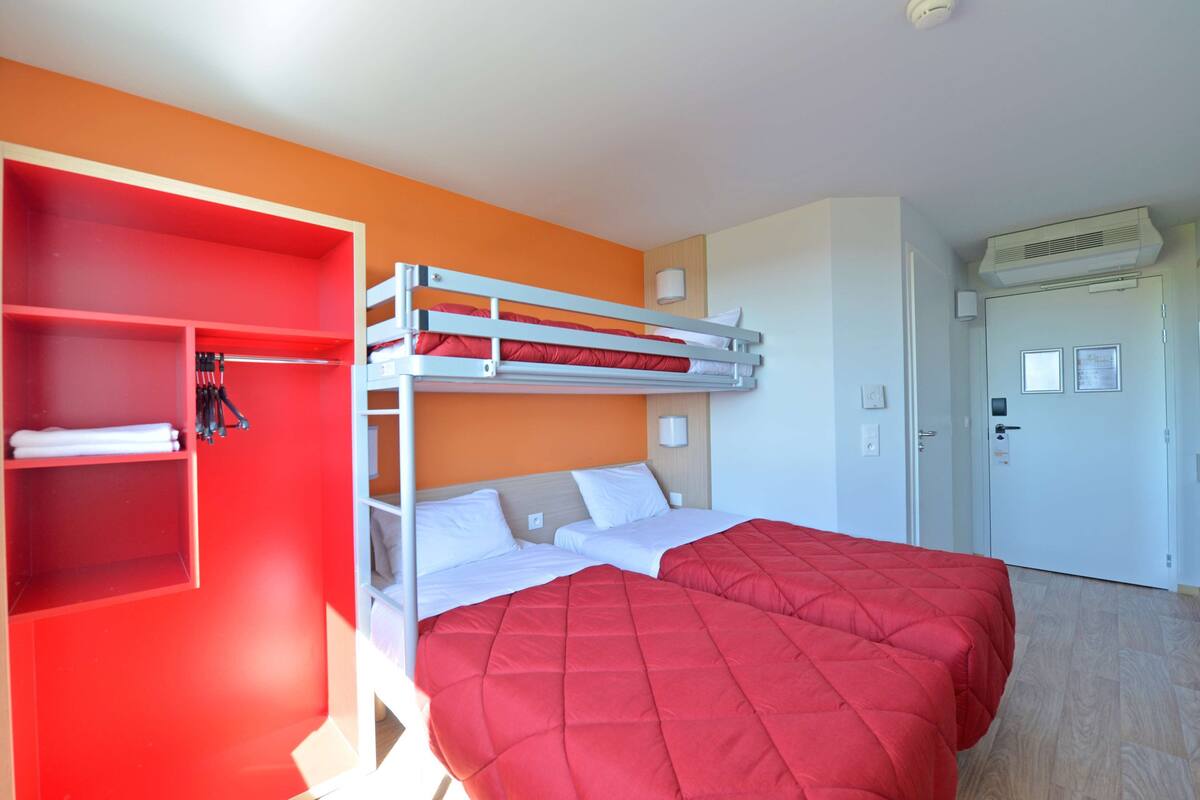 Ein Zimmer mit einem Etagenbett, einem roten Kleiderschrank und einer weißen Tür.