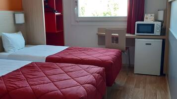 Habitación de hotel con dos camas, un escritorio, microondas y refrigerador.
