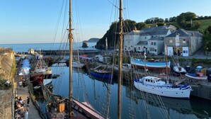 A harbor with multiple boats docked, a prominent building with a sign reading "Brewery House," and a clear view of the sea.