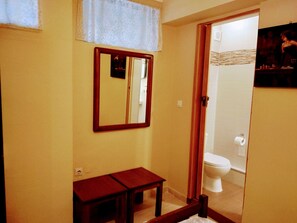 Ein Badezimmer mit einer Holzbank, einem Spiegel und einer Toilette.
