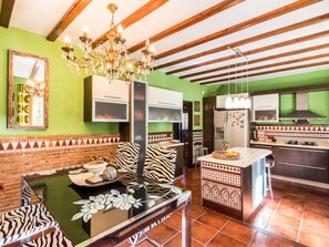 Une cuisine dotée d’un îlot central, de murs verts et d’un lustre.
